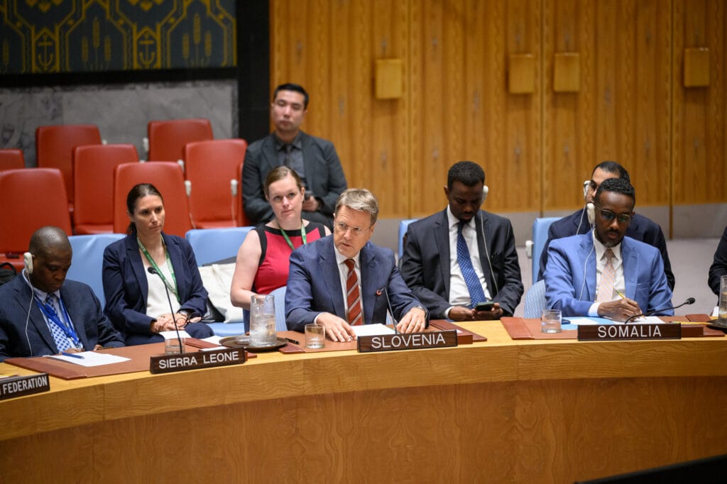 Slovenian Ambassador Žbogar sitting at the table in the UN Security Council Chamber, speaking and surrounded by other people