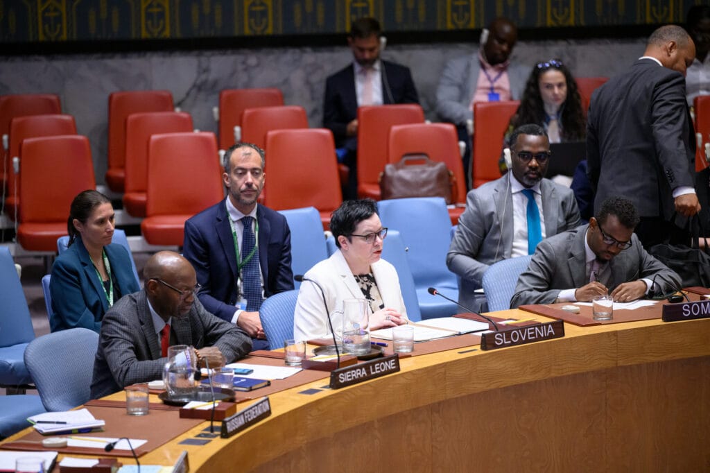Deputy PR of Slovenia to the UN sitting at the table in UN SC Chamber, delivering her statement, surrounded by other people