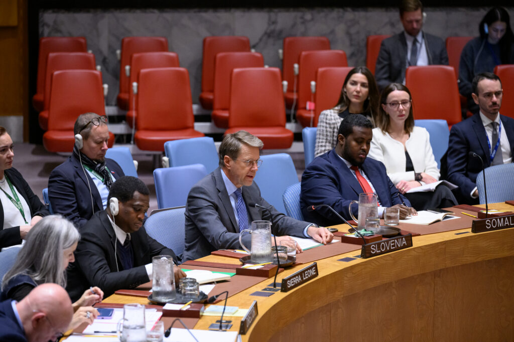 Slovenian Ambassador Žbogar sitting at the table in the UN Security Council Chamber, speaking and surrounded by other people.