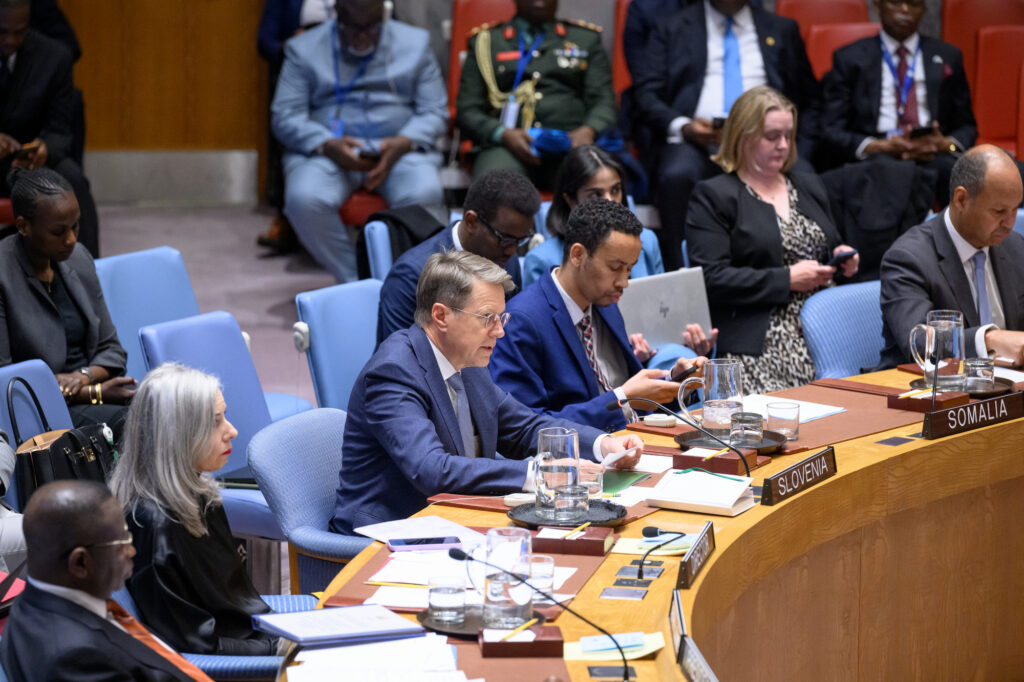Slovenian Ambassador Žbogar sitting at the table in the UN Security Council Chamber, speaking and surrounded by other people.