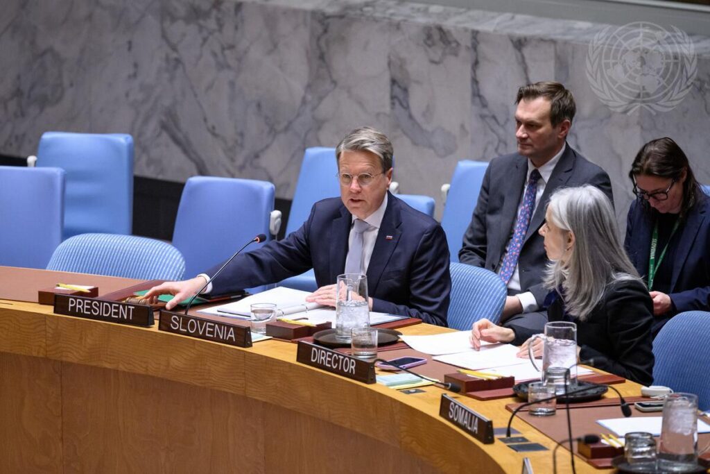 Slovenian Ambassador Žbogar sitting at the table in the UN Security Council Chamber, speaking and surrounded by other people.
