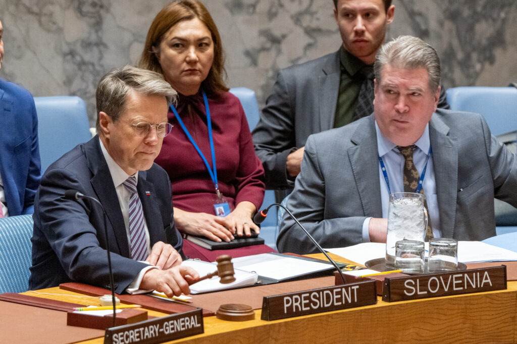 Slovenian Ambassador Žbogar sitting at the table in the UN Security Council Chamber, speaking and surrounded by other people.