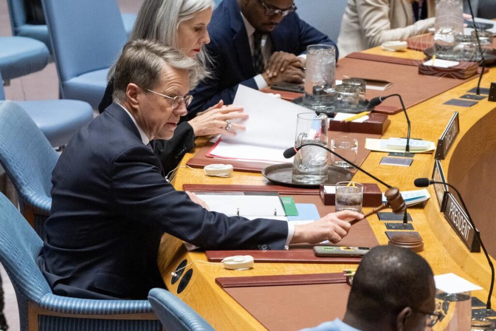 Slovenian Ambassador Žbogar sitting at the table in the UN Security Council Chamber, speaking and surrounded by other people.